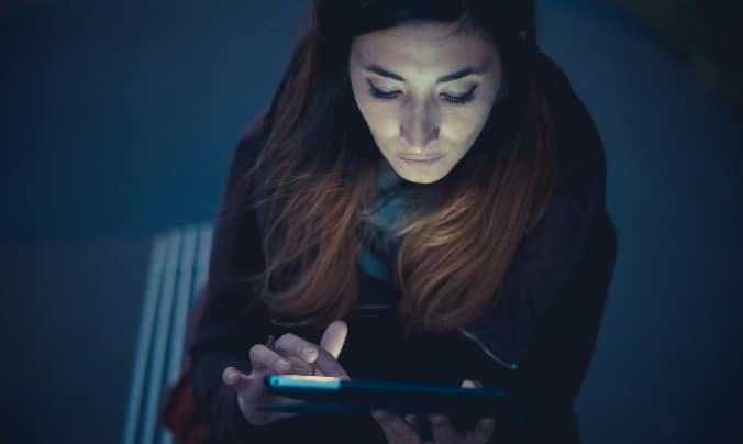 Mid adult woman using digital tablet touchscreen on railway platform at dusk