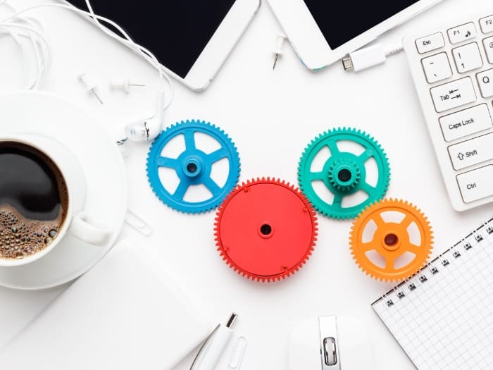 workflow and teamwork concepts with colorful gears different gadgets and office stationery on the white office table